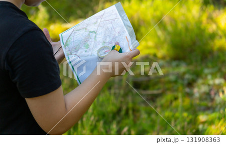 Orienteering athlete running through a summer forest with a map and compass. Orienteering athlete running through a summer forest with a map and compass. 131908363