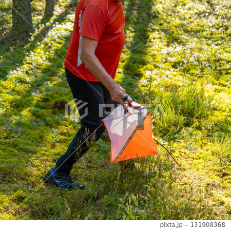 Elderly male orienteer scanning his electronic chip at a control point 131908368