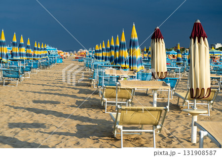 Sun loungers on sandy beach with Umbrellas. Empty seaside resort. Italy. 131908587