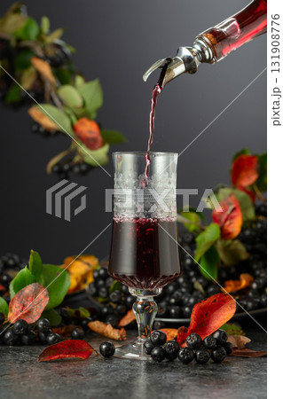 Black chokeberry drink and fresh berries on a black stone table. Black chokeberry drink and fresh berries on a black stone table. 131908776