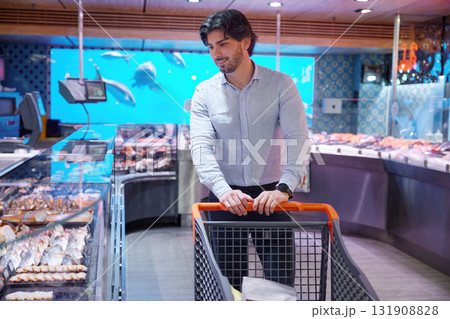 A man pushing a shopping cart in a store A man pushing a shopping cart in a store 131908828