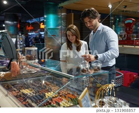 A man and a woman are examining various types of food in a store 131908857