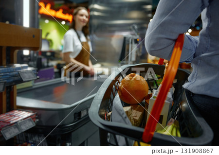 Closeup of man carrying a shopping basket full of groceries to the checkout in a store 131908867