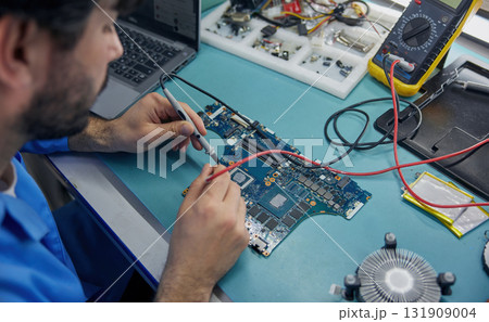 Technician man worker is focused on working with a motherboard Technician man worker is focused on working with a motherboard 131909004