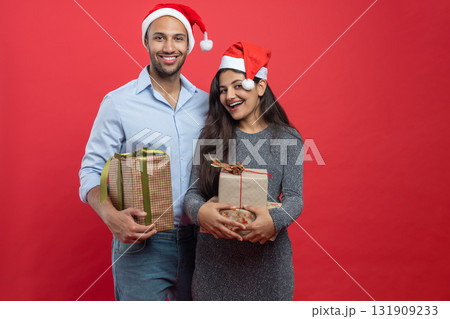 Man and woman dressed in festive attire celebrating new year with gift boxes and tinsel 131909233