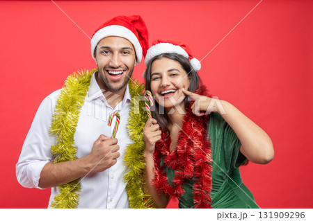 Cheerful family wearing Santa hats celebrating Xmas together with decorations and candy canes Cheerful family wearing Santa hats celebrating Xmas together with decorations and candy canes 131909296