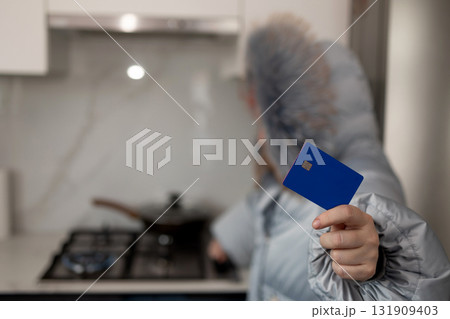Paying Heating Bill in Winter. Woman With Credit Card in Warm Jacket Indoors Paying Heating Bill in Winter. Woman With Credit Card in Warm Jacket Indoors 131909403