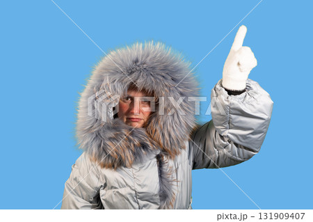 Woman in Winter Coat Points Upward Offering Copy Space Above 131909407