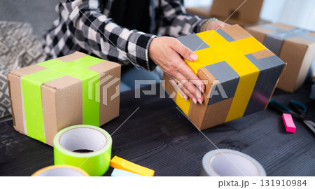 Girl At Home Packing A Cardboard Box, Representing The Concept Of Handmade Products For Selling Online Girl At Home Packing A Cardboard Box, Representing The Concept Of Handmade Products For Selling Online 131910984