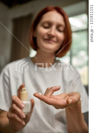Woman applying moisturizing cream on hand with gentle smile and soft natural light Woman applying moisturizing cream on hand with gentle smile and soft natural light 131911151