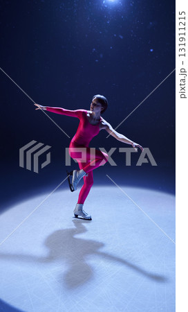 Female figure skater in pink outfit gliding gracefully in balanced one-leg spin on ice 131911215