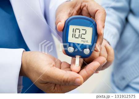 Asian doctor using digital glucose meter for check sample blood sugar level to treatment diabetes. 131912575