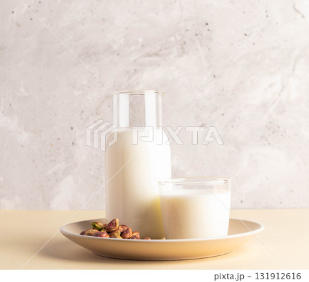 Milk and pistachios arranged on beige plate with textured background for healthy lifestyle concept Milk and pistachios arranged on beige plate with textured background for healthy lifestyle concept 131912616