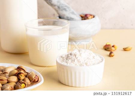 Pistachios, milk, nut flour and nutty milk in bright kitchen setting with natural light and textures 131912617