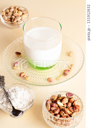 Pistachios and nut milk in glassware with decorative plates and bowls for refined presentation 131912632