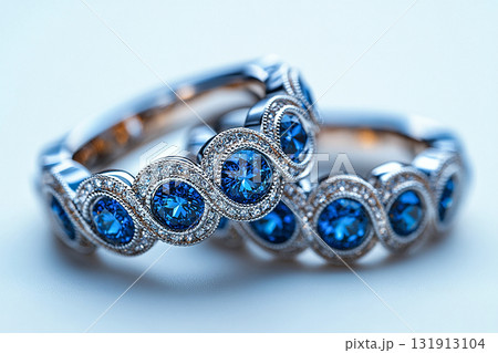 Luxurious pair of wedding rings with blue stones on a white background. Rococo-Renaissance style. 131913104