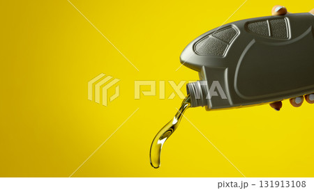 Close up of gray oil bottle pouring transparent motor fluid on bright yellow background Close up of gray oil bottle pouring transparent motor fluid on bright yellow background 131913108