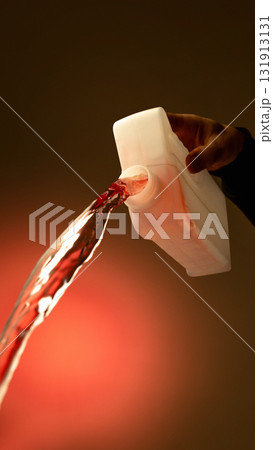 Red automotive fluid pouring from white plastic container with warm lighting Red automotive fluid pouring from white plastic container with warm lighting 131913131