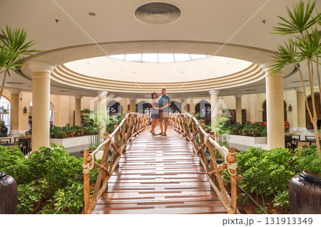 Loving adults stand hugging on a decorative bridge inside a building 131913349