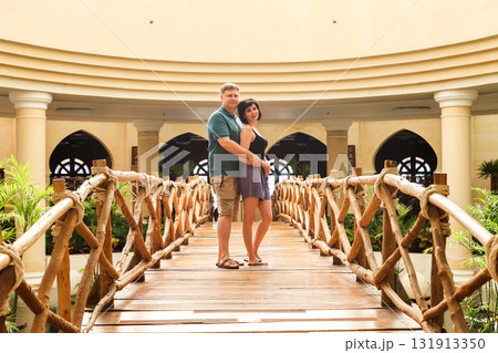Loving adults stand hugging on a decorative bridge inside a building 131913350