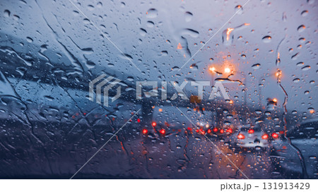 Atmospheric view of a rainy highway at dusk with water on the windshield and blurred taillights 131913429