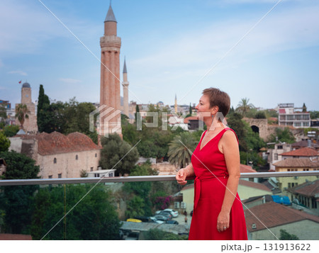 Woman in red dress walking narrow streets of old town Antalya during warm summer evening. Historic atmosphere and Mediterranean charm creates peaceful travel experience. view on Kalechi Woman in red dress walking narrow streets of old town Antalya during warm summer evening. Historic atmosphere and Mediterranean charm creates peaceful travel experience. view on Kalechi 131913622