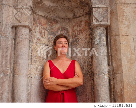 Woman in red dress walking narrow streets of old town Antalya during warm summer evening. Historic atmosphere and Mediterranean charm creates peaceful travel experience. near old mosque Woman in red dress walking narrow streets of old town Antalya during warm summer evening. Historic atmosphere and Mediterranean charm creates peaceful travel experience. near old mosque 131913631