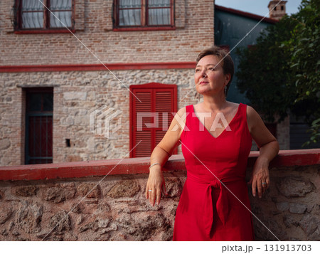 Woman in red dress walking narrow streets of old town Antalya during warm summer evening. Historic atmosphere and Mediterranean charm creates peaceful travel experience. 131913703