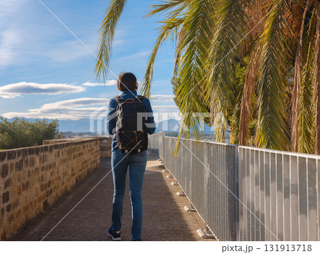 Young woman exploring historic castle in Denia, Alicante province, Spain, scenic views of town below, set against cooler season backdrop. blend of history and tranquility in timeless setting. 131913718