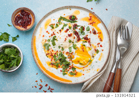 Turkish eggs cilbir, Middle Eastern style breakfast on blue background table top view Turkish eggs cilbir, Middle Eastern style breakfast on blue background table top view 131914321