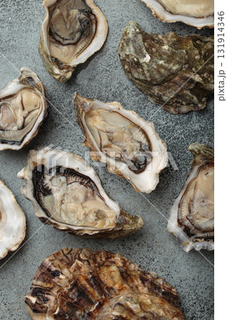 Fresh opened oysters scattered on dark gray surface top view Fresh opened oysters scattered on dark gray surface top view 131914346