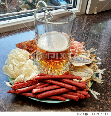 A glass of beer and dried seafood as an appetizer to go with the drink 131914814