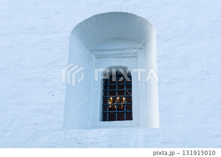 window in the facade of medieval building, behind which a chandelier with candles is visible window in the facade of medieval building, behind which a chandelier with candles is visible 131915010