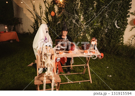 Senior woman and ghost celebrating Halloween in the garden 131915594