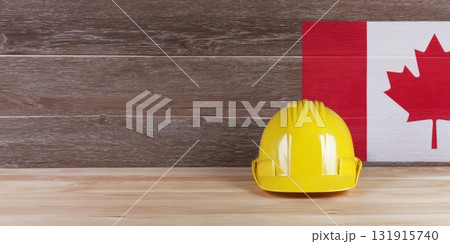 Yellow hard hat with canadian flag on wooden background 131915740