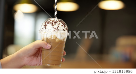 Holding iced coffee frappuccino with whipped cream 131915986