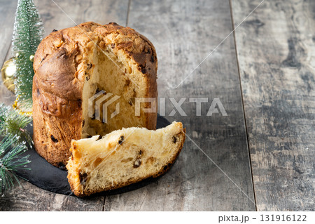 Traditional Italian Panettone on wooden table and christmas tree Traditional Italian Panettone on wooden table and christmas tree 131916122