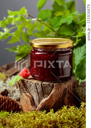 A jar of raspberry jam with fresh berries on an old tree trunk in the forest. A jar of raspberry jam with fresh berries on an old tree trunk in the forest. 131916878