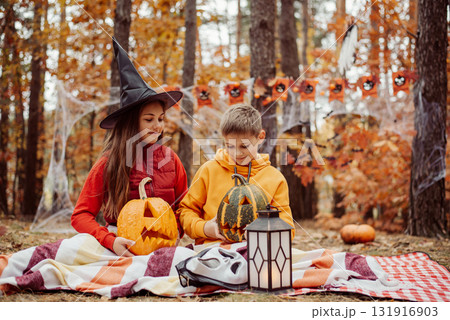 Brother and sister preparing halloween decoration in the forest. Concept of autumn holiday, family together during holidays. Brother and sister preparing halloween decoration in the forest. Concept of autumn holiday, family together during holidays. 131916903