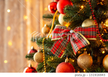 Close-up shot of bow on Christmas tree. Beautifully decorated fir tree with baubles, beads, bright bows, Christmas celebration Close-up shot of bow on Christmas tree. Beautifully decorated fir tree with baubles, beads, bright bows, Christmas celebration 131916943