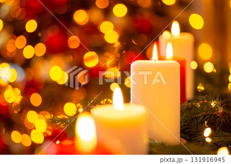 Close-up shot of bright candles in front of fir tree in lights. Celebrating Christmas concept Close-up shot of bright candles in front of fir tree in lights. Celebrating Christmas concept 131916945