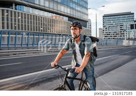 Urban commuter cycling on street carrying backpack. Urban commuter cycling on street carrying backpack. 131917185