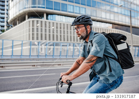 Urban commuter cycling on street carrying backpack. Urban commuter cycling on street carrying backpack. 131917187