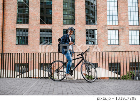 City commuter riding bike from work, reading text message on phone. City commuter riding bike from work, reading text message on phone. 131917208