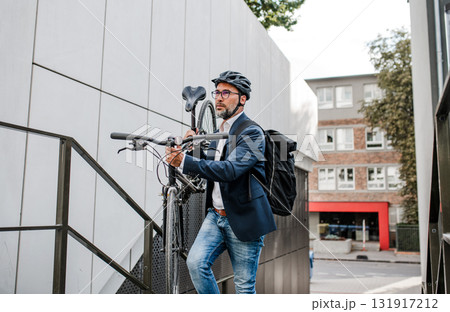 City commuter carrying bicycle up urban stairs. City commuter carrying bicycle up urban stairs. 131917212