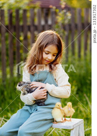Smiling child playing with baby animals in the garden. Smiling child playing with baby animals in the garden. 131917302