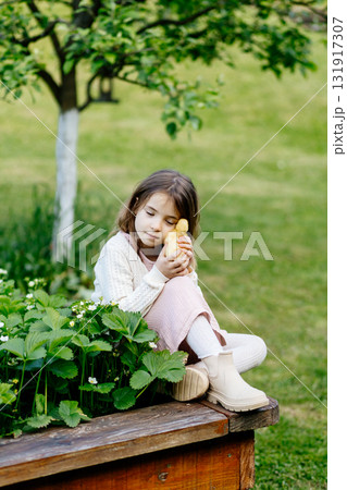 Young girl in garden playing with baby duckling. 131917307