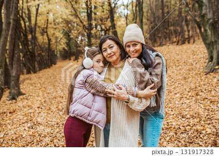 Mature daughter, grandmother and granddaugter on walk in autumn forest. 131917328