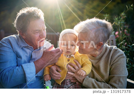 Grandparents holding baby in warm embrace during fall season. 131917378