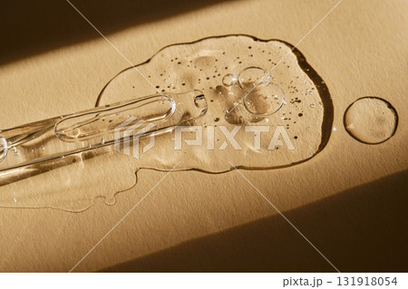 A pipette with cosmetic serum on a beige background. A pipette with cosmetic serum on a beige background. 131918054